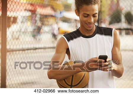 Man using cell phone on basketball court View Large Photo Image Stock Photograph - Man using cell phone on basketball court. Fotosearch