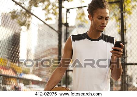 Man using cell phone on basketball court View Large Photo Image Stock Photography - Man using cell phone on basketball court. Fotosearch