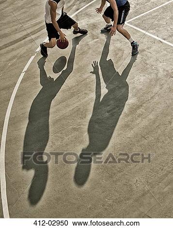 Stock Image - Men playing basketball on court. Fotosearch