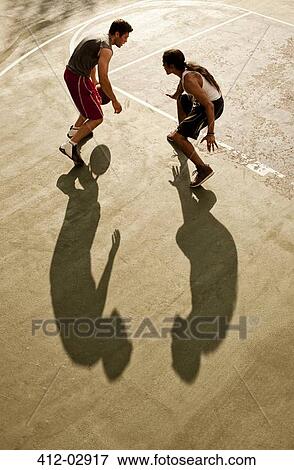 Stock Photo - Men playing basketball on court. Fotosearch