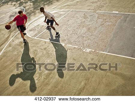 Stock Photo - Men playing basketball on court. Fotosearch