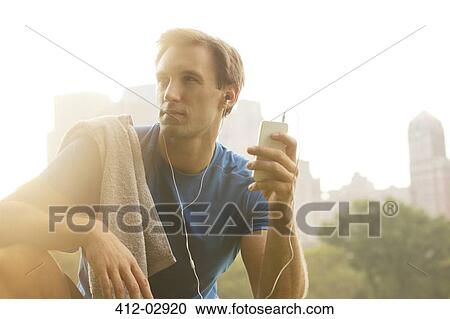 Runner listening to mp3 player in park View Large Photo Image Stock Image - Runner listening to mp3 player in park. Fotosearch