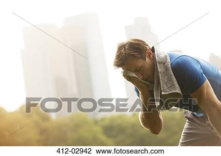 Stock Image - Runner resting in urban park. Fotosearch