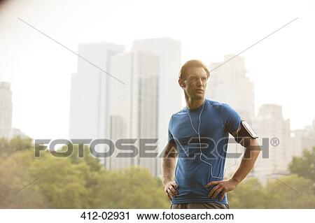 Stock Image - Runner standing in urban park. Fotosearch