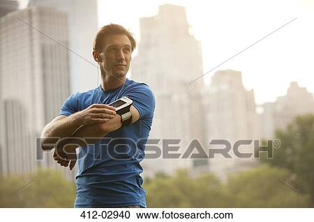 Stock Image - Runner stretching in urban park. Fotosearch