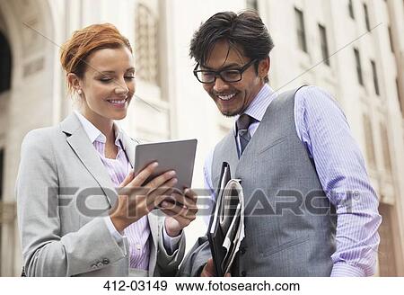 Stock Photo - Business people using tablet computer on city street. Fotosearch