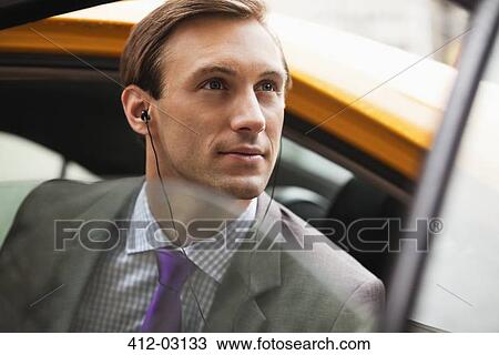 Stock Image - Businessman climbing out of taxi on city street. Fotosearch