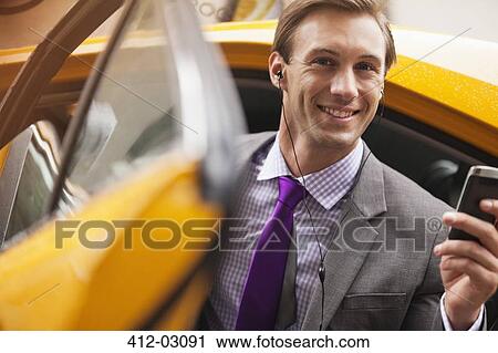 Stock Image - Businessman climbing out of taxi. Fotosearch