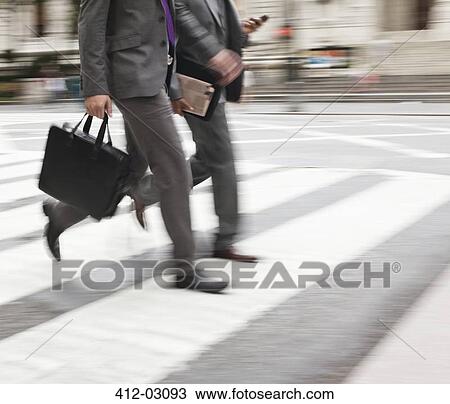 Stock Image - Businessman crossing city street. Fotosearch