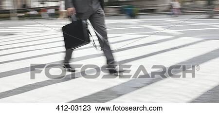 Stock Image - Businessman crossing city street. Fotosearch