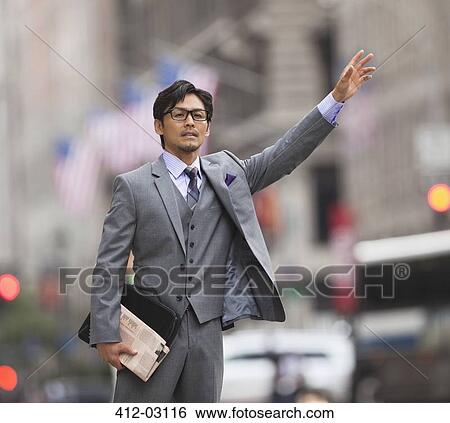 Businessman hailing taxi on city street View Large Photo Image Stock Photograph - Businessman hailing taxi on city street. Fotosearch