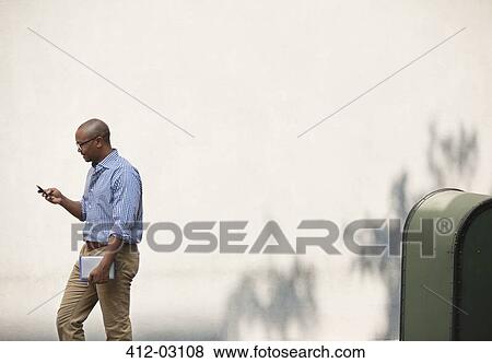 Businessman using cell phone in urban park View Large Photo Image Stock Photo - Businessman using cell phone in urban park. Fotosearch