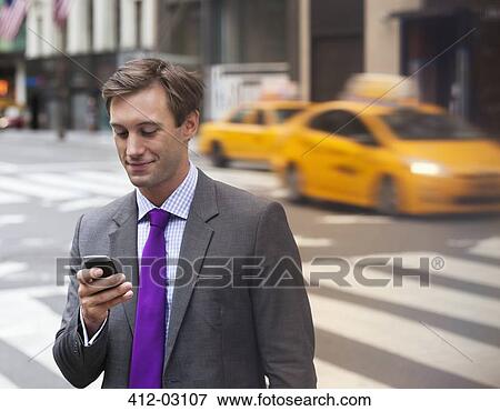 Stock Photo - Businessman using cell phone on city street. Fotosearch