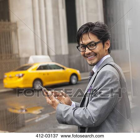 Businessman using cell phone on city street View Large Photo Image Stock Photo - Businessman using cell phone on city street. Fotosearch