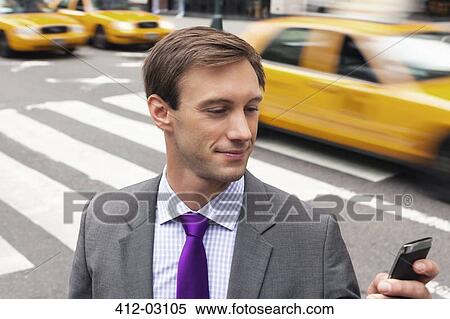 Businessman using cell phone on city street View Large Photo Image Stock Photography - Businessman using cell phone on city street. Fotosearch
