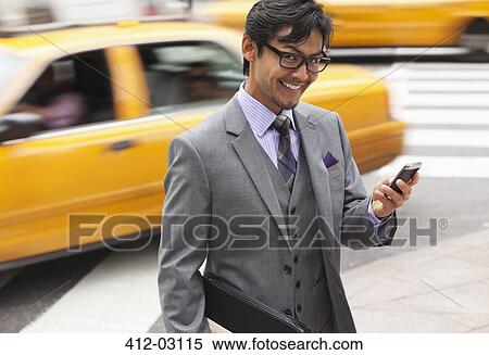 Stock Photography - Businessman using cell phone on city street. Fotosearch