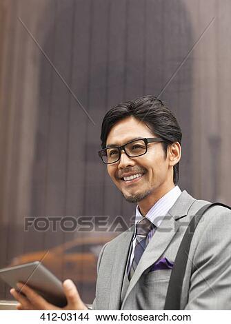 Picture - Businessman using tablet computer on city street. Fotosearch