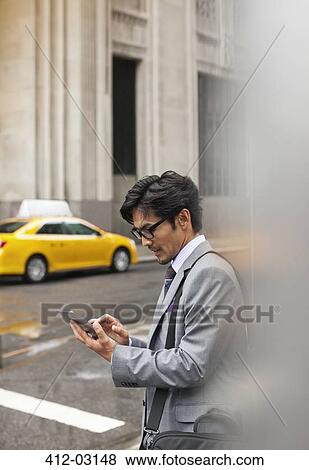 Businessman using tablet computer on city street View Large Photo Image Stock Photo - Businessman using tablet computer on city street. Fotosearch