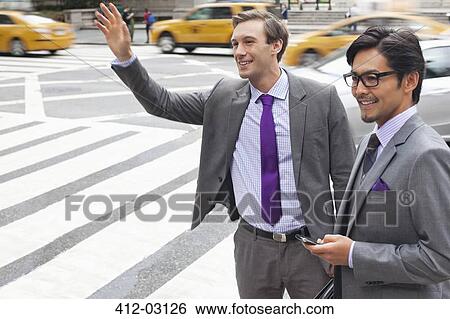 Businessmen hailing taxi on city street View Large Photo Image Stock Photograph - Businessmen hailing taxi on city street. Fotosearch