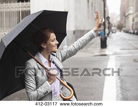 Businesswoman hailing taxi on city street View Large Photo Image Stock Photo - Businesswoman hailing taxi on city street. Fotosearch