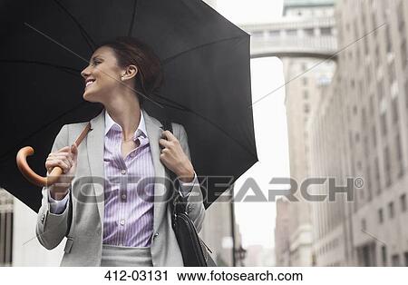Businesswoman holding umbrella on city street View Large Photo Image Stock Image - Businesswoman holding umbrella on city street. Fotosearch