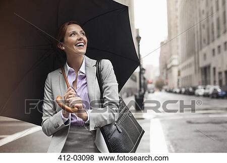 Businesswoman holding umbrella on city street View Large Photo Image Stock Photo - Businesswoman holding umbrella on city street. Fotosearch