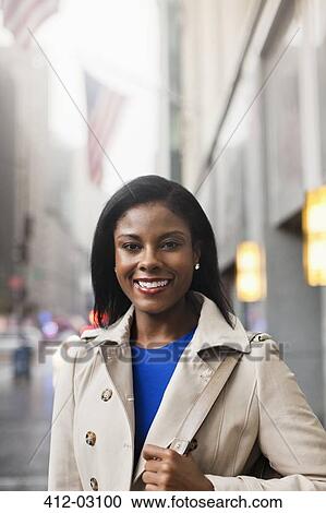 Stock Image - Businesswoman smiling on city street. Fotosearch