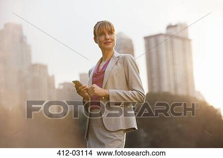 Businesswoman using cell phone in urban park View Large Photo Image Picture - Businesswoman using cell phone in urban park. Fotosearch
