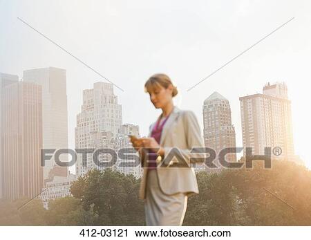 Businesswoman using cell phone in urban park View Large Photo Image Stock Image - Businesswoman using cell phone in urban park. Fotosearch