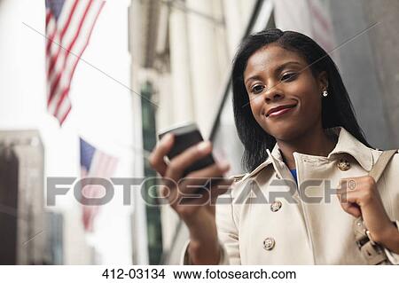Picture - Businesswoman using cell phone on city street. Fotosearch