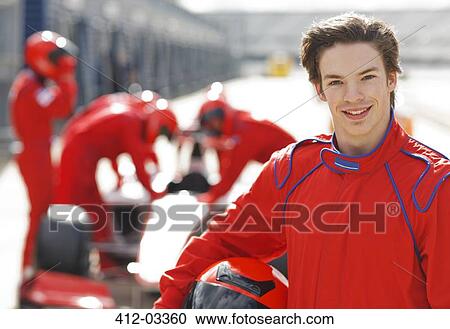 Stock Image - Racer holding helmet on track. Fotosearch