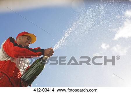 Racer spraying bottle of champagne outdoors View Large Photo Image Picture - Racer spraying bottle of champagne outdoors. Fotosearch