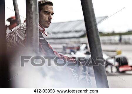 Stock Image - Racer standing on sidelines on track. Fotosearch