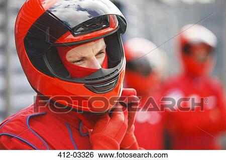 Stock Photograph - Racer tying on helmet on track. Fotosearch