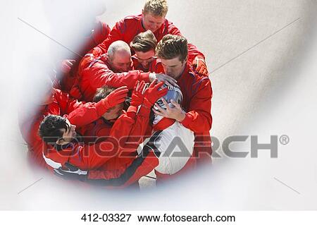 Stock Photo - Racing team hugging racer at pit stop. Fotosearch