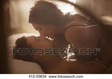 Picture - Couple kissing on bed. Fotosearch