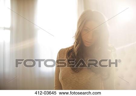 Stock Photography - Woman sitting in bedroom. Fotosearch