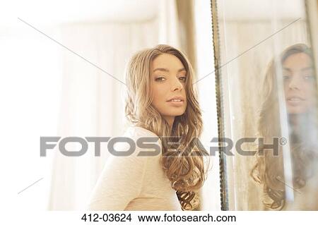 Woman standing by mirror View Large Photo Image Picture - Woman standing by mirror. Fotosearch