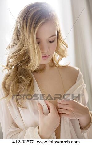 Stock Image - Woman wearing sheer top in bedroom. Fotosearch