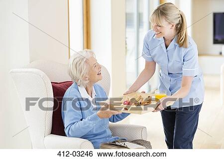 Caregiver giving older woman tray of food View Large Photo Image Stock Photograph - Caregiver giving older woman tray of food. Fotosearch