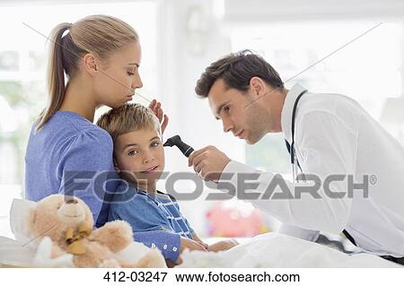 Doctor examining boy's ear at house call View Large Photo Image Stock Photo - Doctor examining boy's ear at house call. Fotosearch