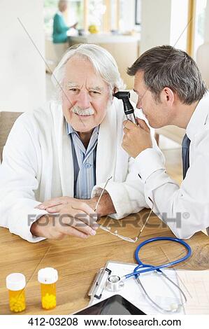 Doctor examining older man's ear at house call View Large Photo Image Stock Photo - Doctor examining older man's ear at house call. Fotosearch