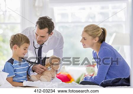 Picture - Doctor listening to teddy bear's heartbeat at house call. Fotosearch