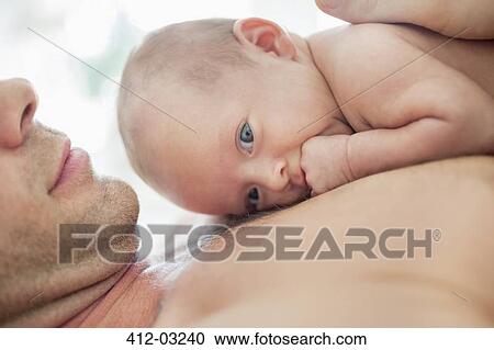 Stock Image - Father cradling newborn baby on chest. Fotosearch