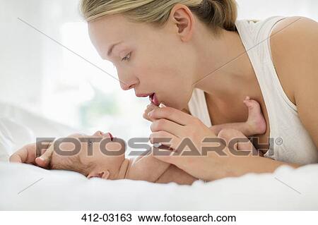 Mother cradling newborn infant on bed View Large Photo Image Stock Image - Mother cradling newborn infant on bed. Fotosearch