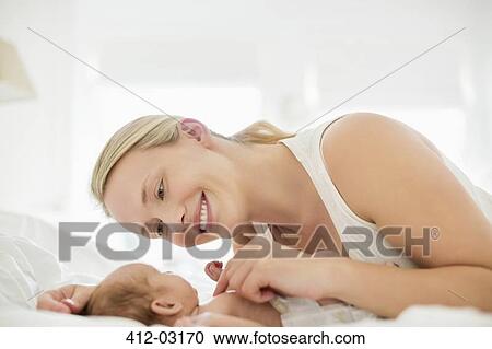 Mother cradling newborn infant on bed View Large Photo Image Stock Image - Mother cradling newborn infant on bed. Fotosearch