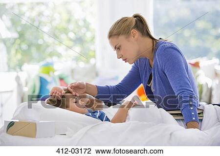 Stock Image - Mother feeling son's forehead. Fotosearch