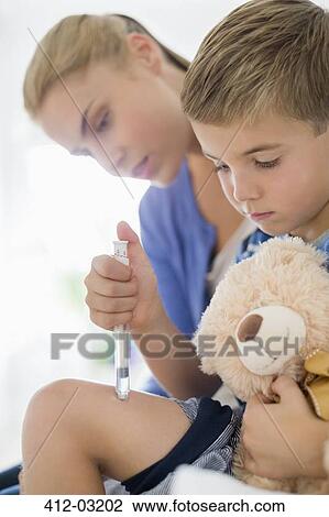 Stock Image - Mother giving son injection in leg. Fotosearch