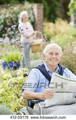 Older man in wheelchair reading newspaper outdoors View Large Photo Image Stock Photo - Older man in wheelchair reading newspaper outdoors. Fotosearch