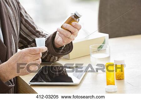 Older man taking medications at table View Large Photo Image Stock Photography - Older man taking medications at table. Fotosearch